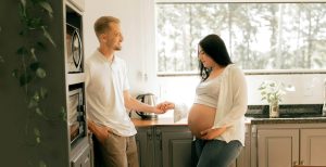 Pregnant woman standing in the kitchen holding her partners hand