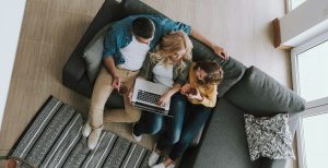 Family sitting on the sofa using a laptop