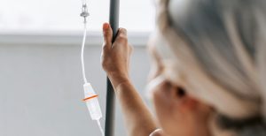 A woman in hospital holding the pole supporting her IV drip