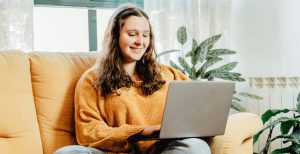 A woman sitting on the sofa looking at her laptop
