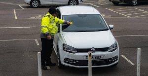 A parking ticket being give out by a parking attendant to a white polo which will lead to someone getting a CCJ