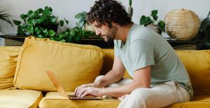 Man sitting on sofa and using his laptop to check his credit score