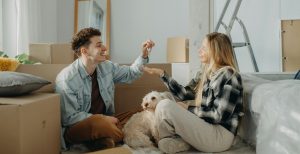 A man passing the keys to his partner in their new house with moving in boxes all around the room