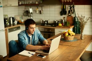 A buy to let landlord on his laptop in the kitchen looking at properties to invest in