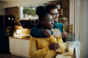 A young couple drinking champagne in their kitchen after moving into their new home