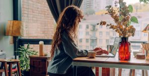 A women sitting in her kitchen working on her laptop