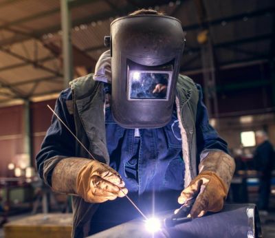 A man weltering a metal sculpture at a table