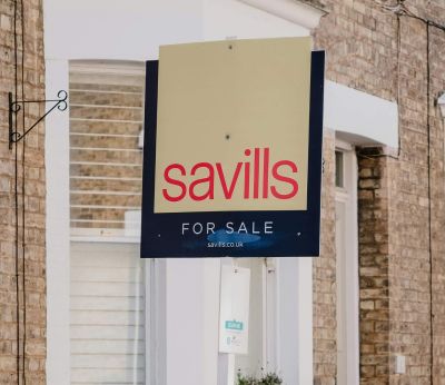 A 'for sale' sign outside a brick house