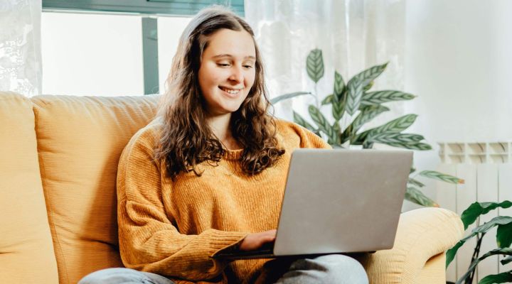 A woman sitting on the sofa looking at her laptop