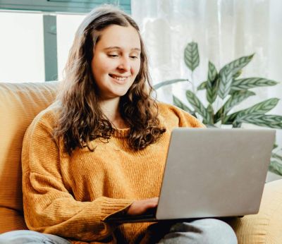 A woman sitting on the sofa looking at her laptop