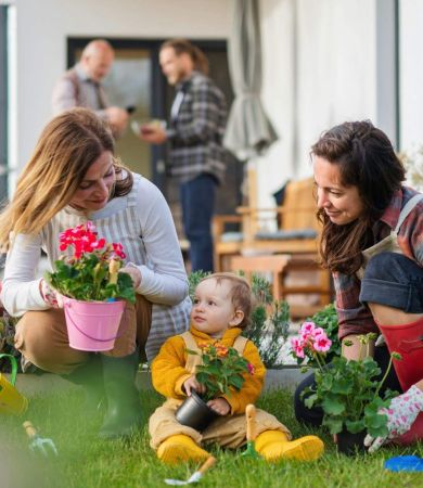 A happy multigeneration family planting flowers in their garden
