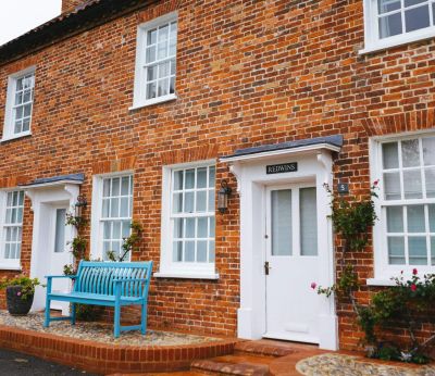 Brick terraced houses with white framed windows and a blue bench out front