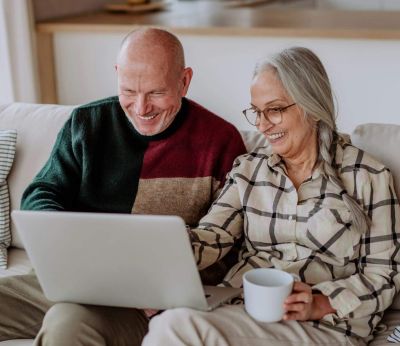 A couple aged 50+ sitting on the sofa looking at their laptop