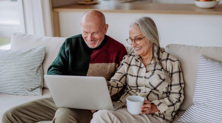 A couple aged 50+ sitting on the sofa looking at their laptop