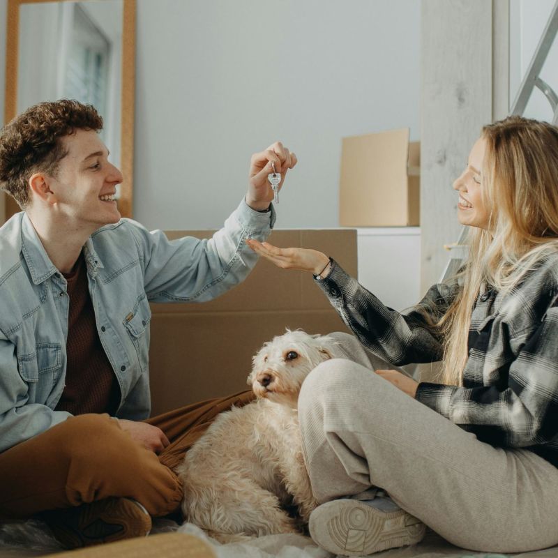 A man passing the keys to his partner in their new house with moving in boxes all around the room