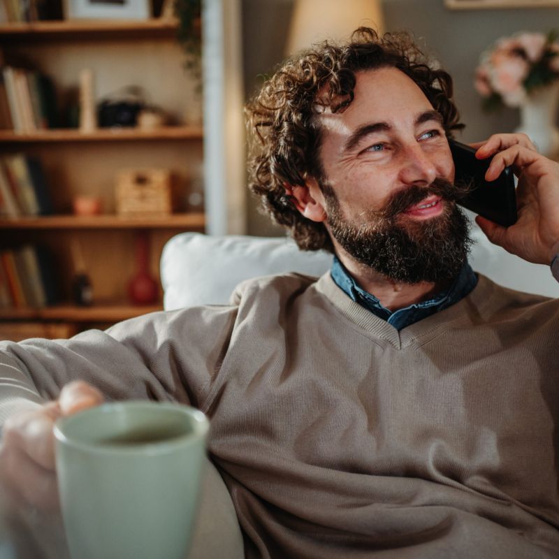 Man on the phone with a cup of coffee in his other hand