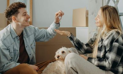 A man passing the keys to his partner in their new house with moving in boxes all around the room