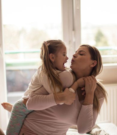Mother and daughter playing on bed