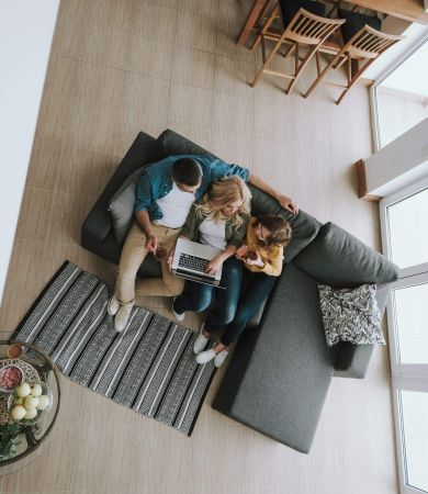 Top view portrait of a family sitting on couch and watching videos on laptop they drinking tea and chatting