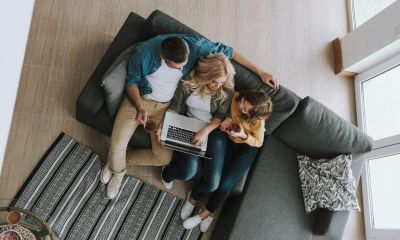 Top view portrait of a family sitting on couch and watching videos on laptop they drinking tea and chatting