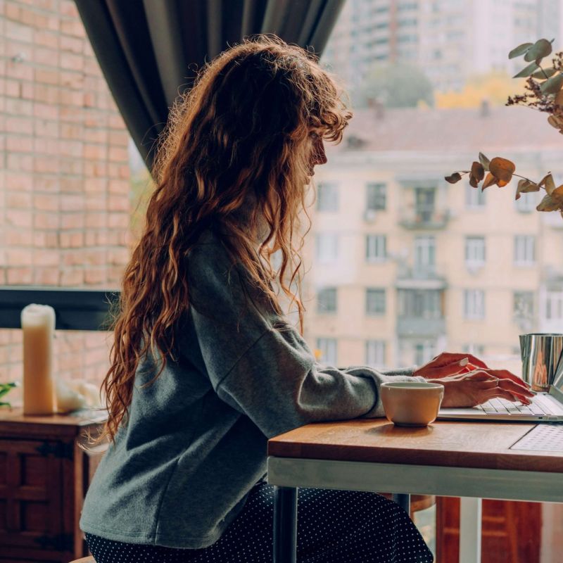 A women sitting in her kitchen working on her laptop