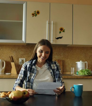 A woman looking over her documents for remortgaging while sitting in her kitchen