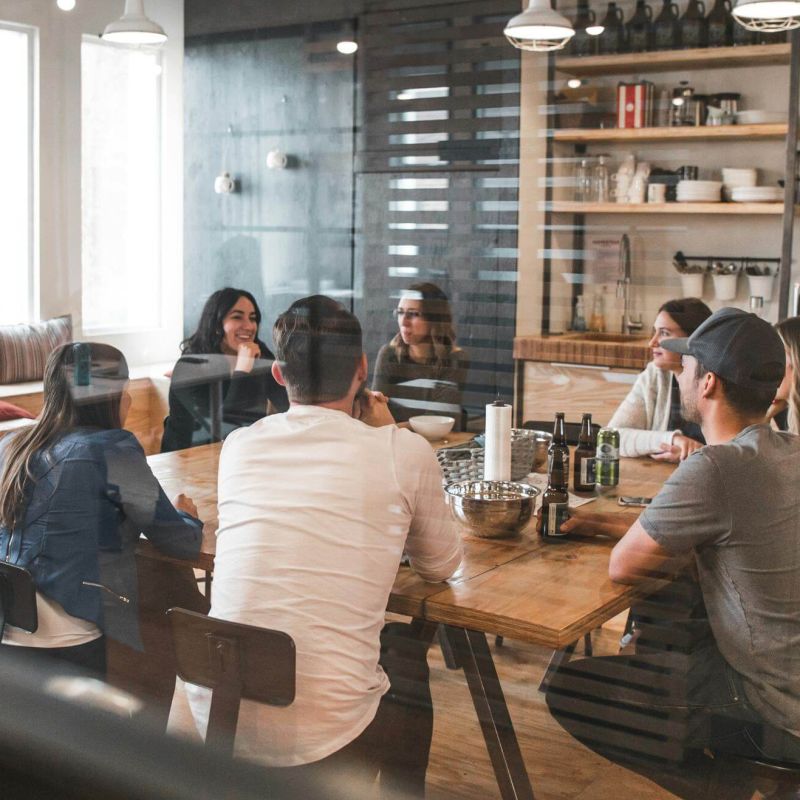People working for a business sitting around and talking to each other after work while having a drink